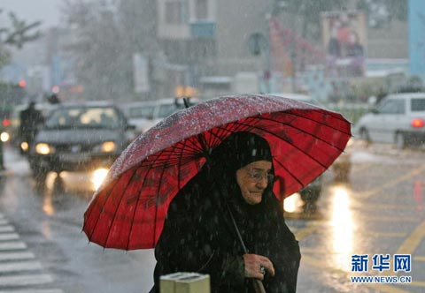 一女子在伊朗首都德黑兰街头冒雪前行